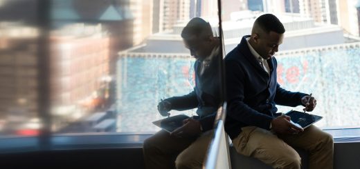 Someone using tablet/laptop seated by a big window