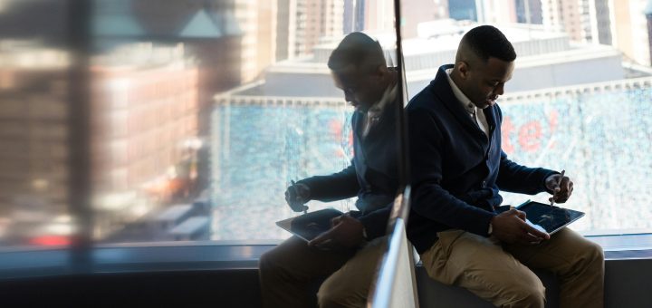 Someone using tablet/laptop seated by a big window