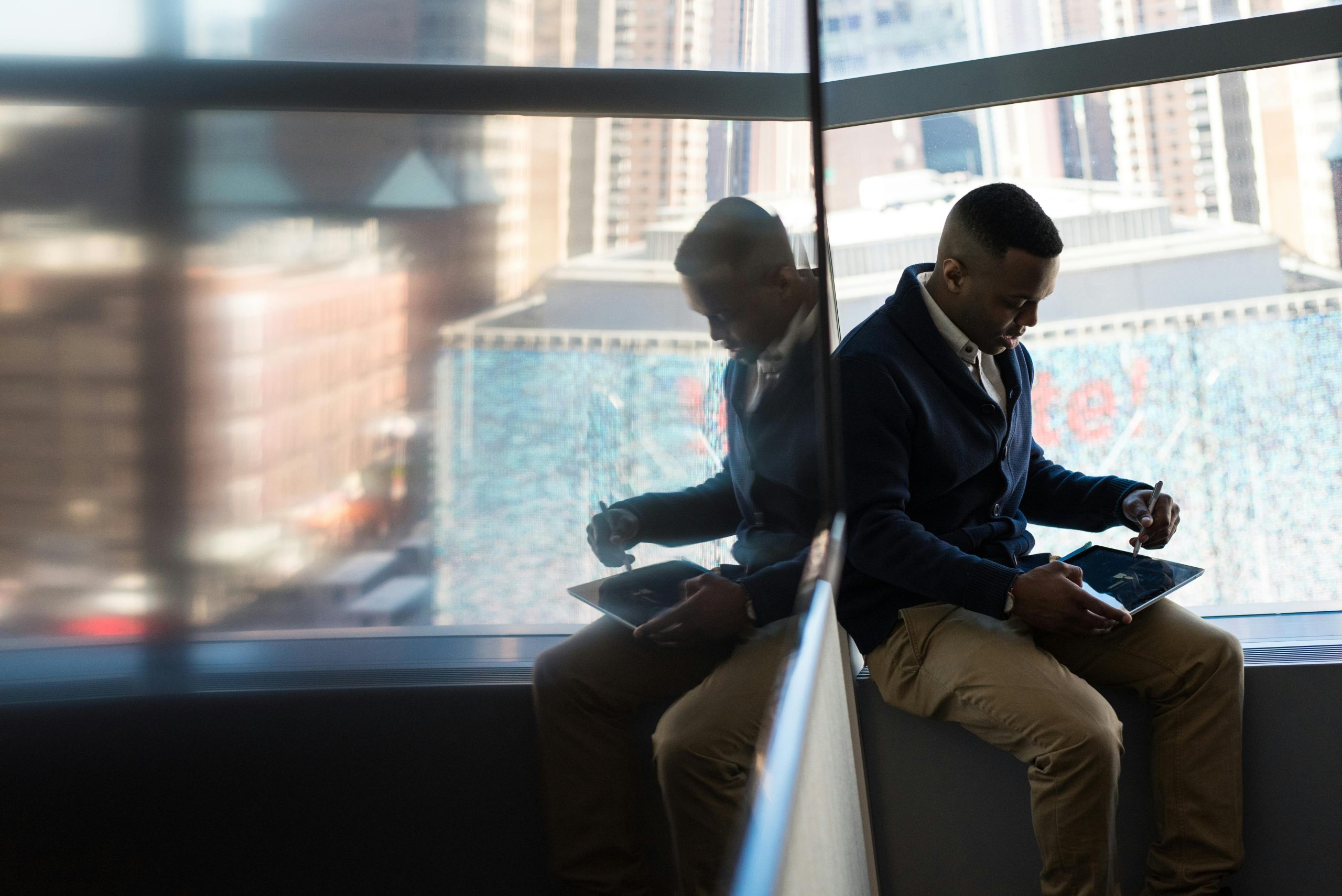 Someone using tablet/laptop seated by a big window